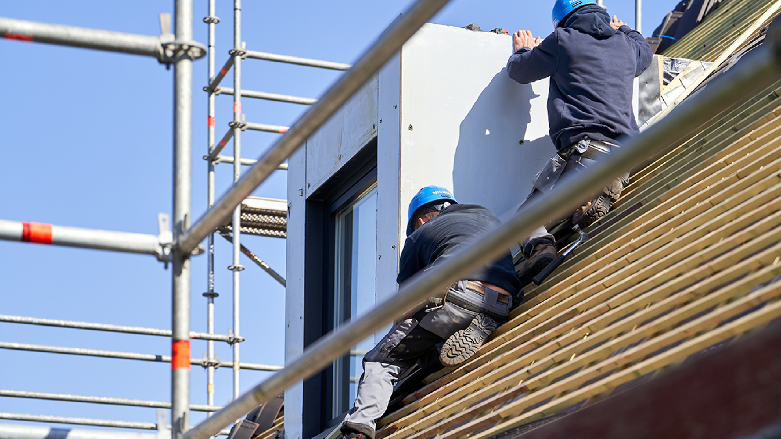 Stelling met dakwerkers op hellend dak