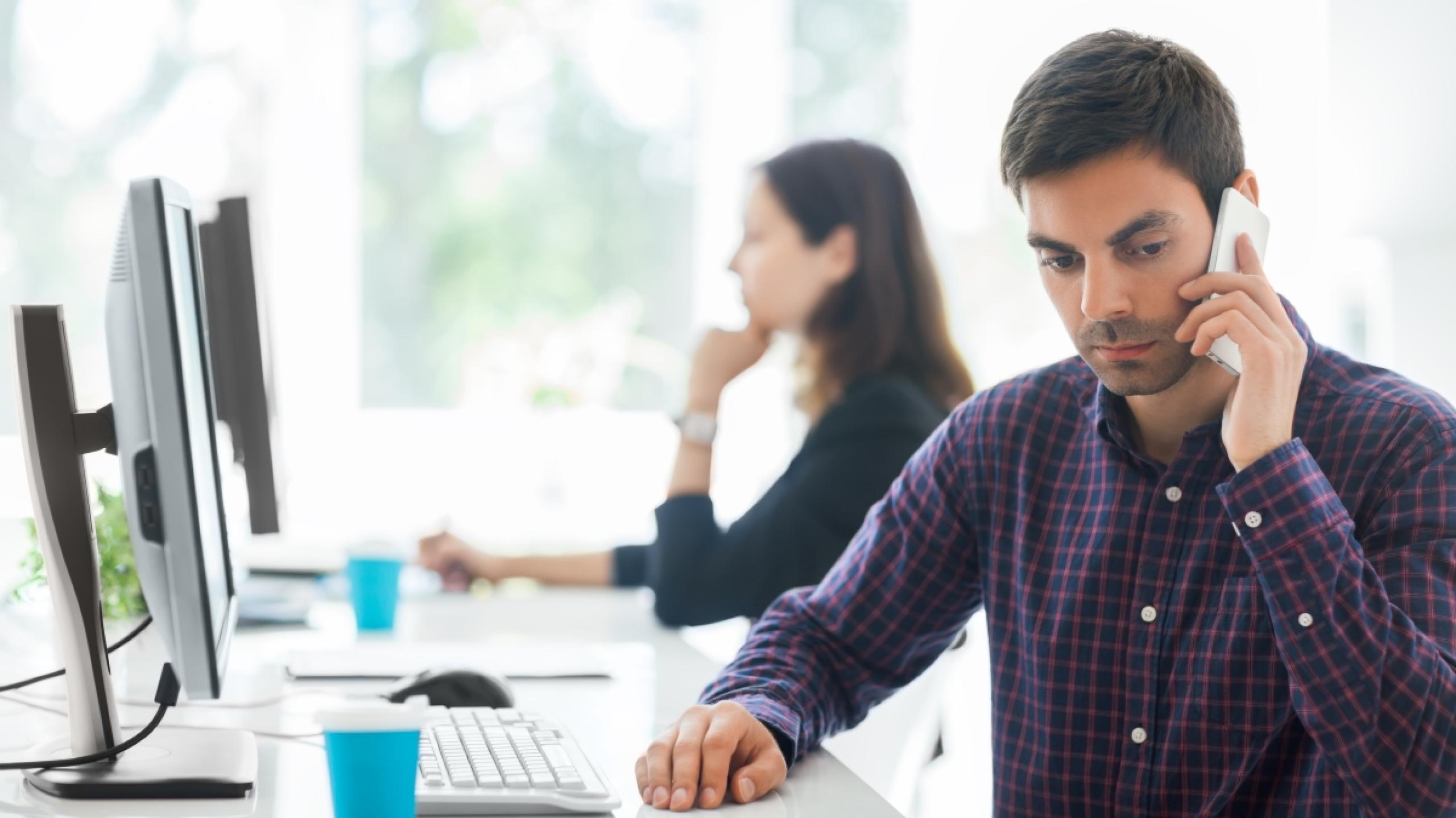 Man op kantoor is stiekem aan het bellen