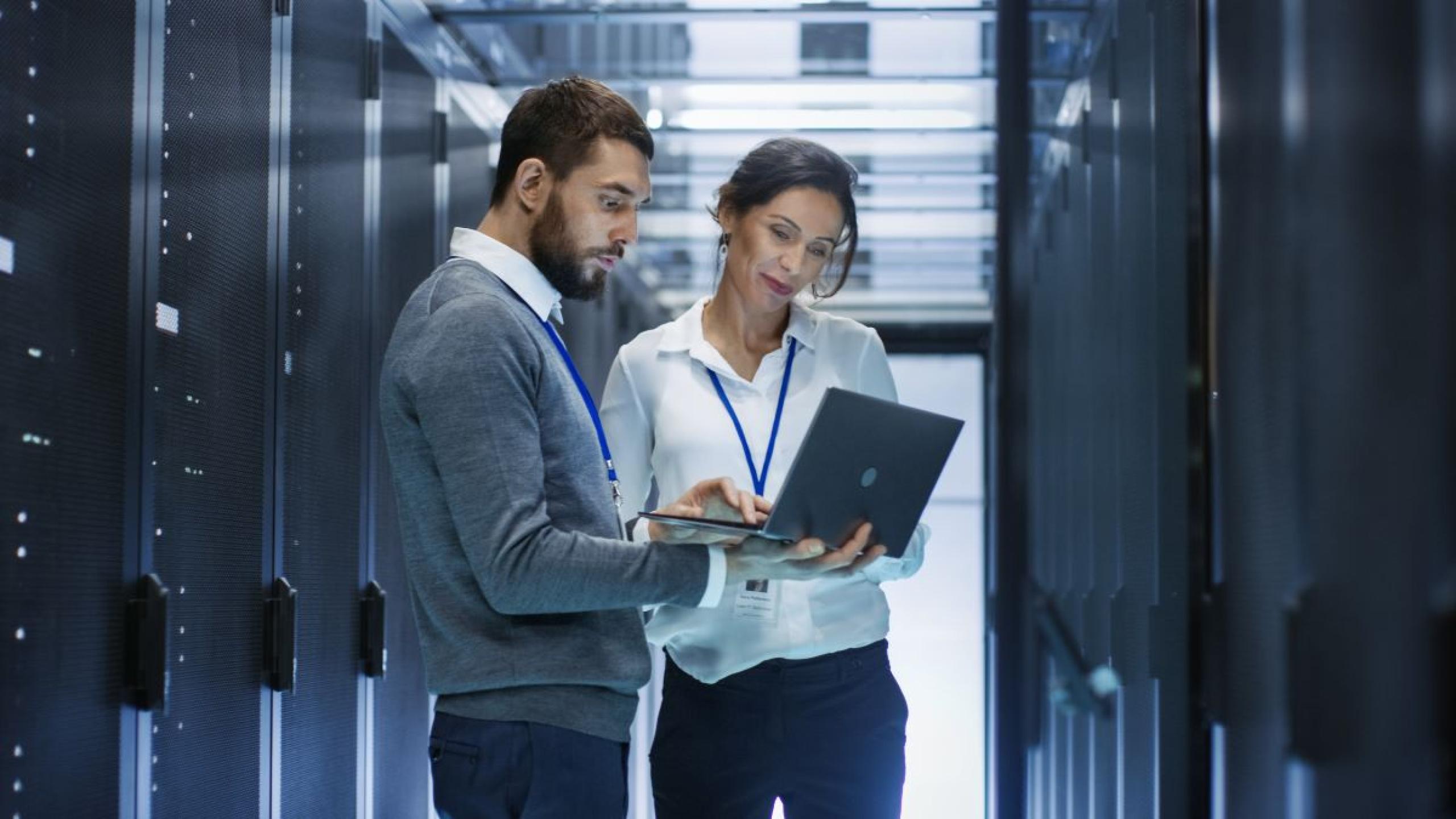 Man en vrouw met laptop in datacenter.