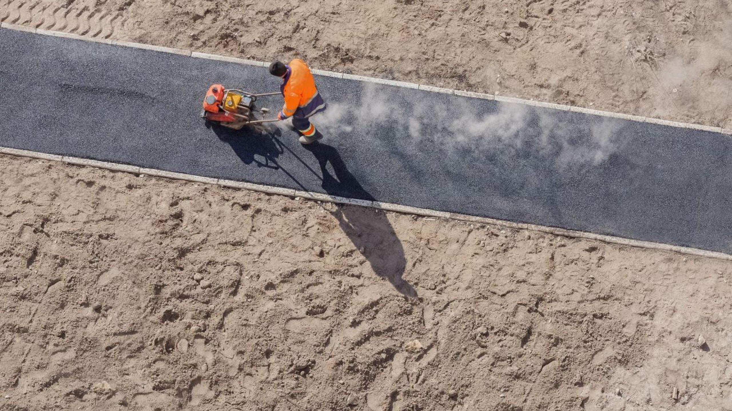 Topshot van arbeider op nieuw fietspad. 