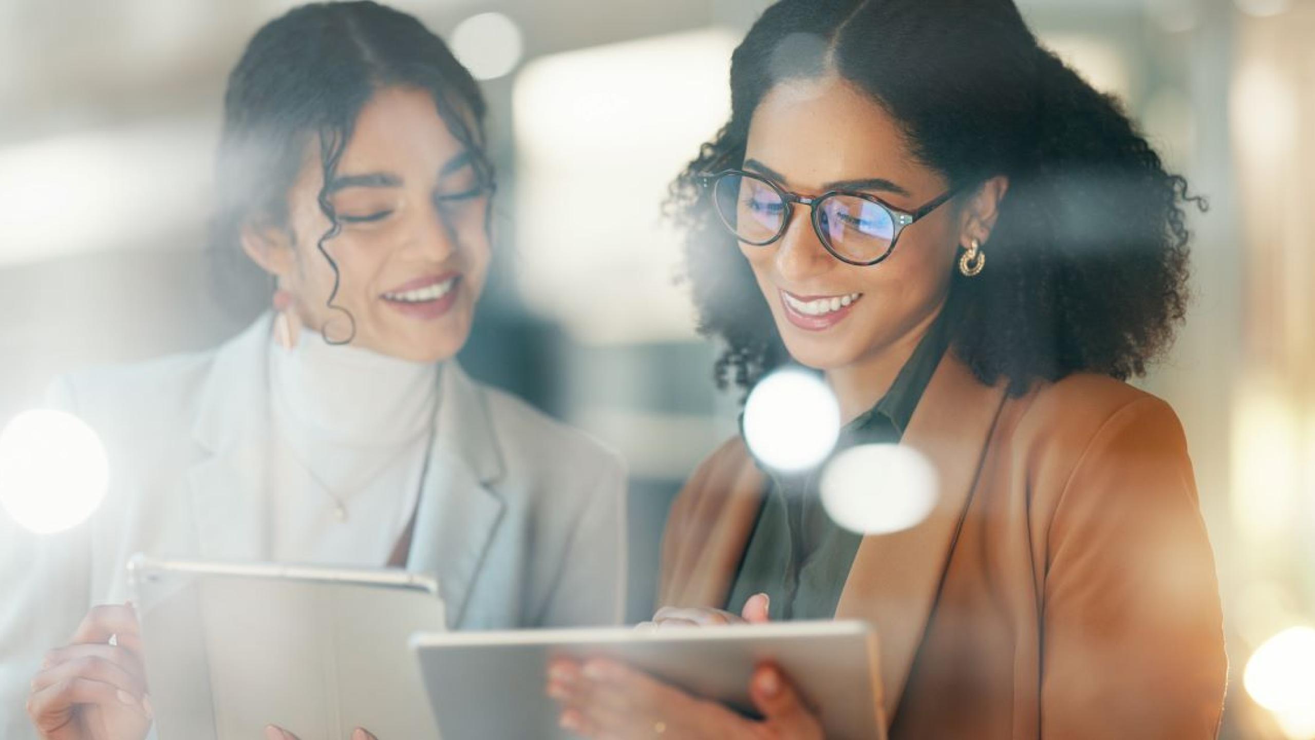 Twee jonge vrouwen vergelijken informatie op hun tablets.